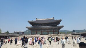 A crowd of visitors in front of Geunjeongmun Gate at Gyeongbokgung Palace on a clear day